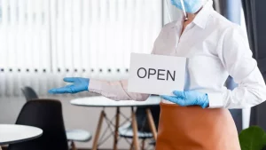 Waitress with PPE holding open sign