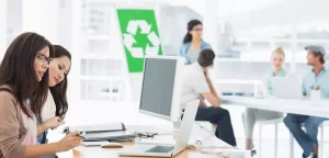 People working at a computer with a recycling sign in background