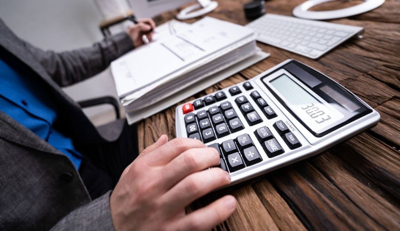 Man with calculator exploring audits of privately held businesses