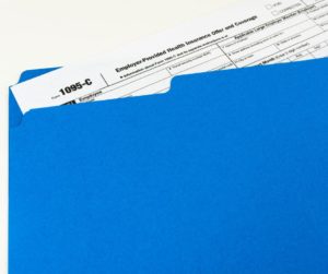 Form 1095-C sticking out of a blue file folder