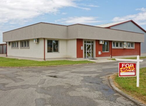 Building with a for sale sign in front of it