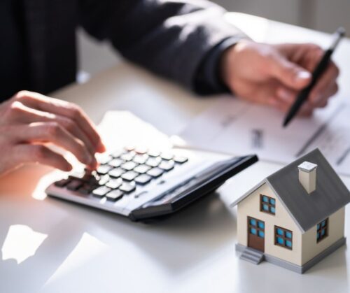 Man working on calculator with a house in the corner